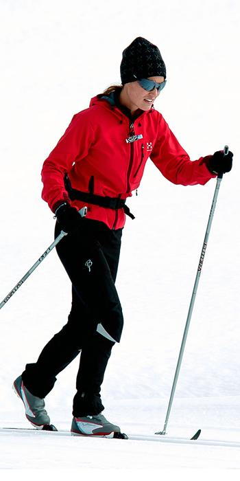 بيبا Middleton - red ski jacket, black snow pants, a black hat, and sporty shades